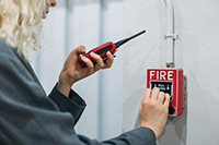 Worker holding red walkie talkie checking fire alarm service in NJ