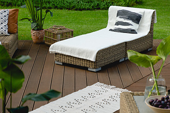 Brown composite deck built by Bayville deck builders with a lounger and plants